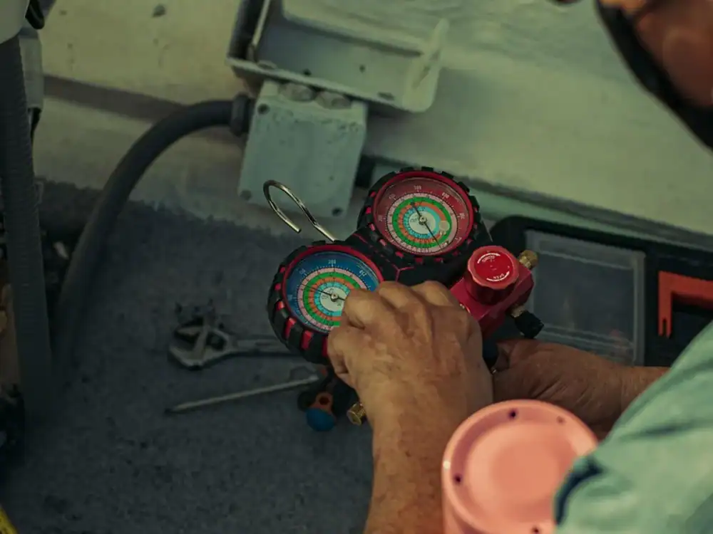 HVAC technician using refrigerant gauges to service an air conditioner