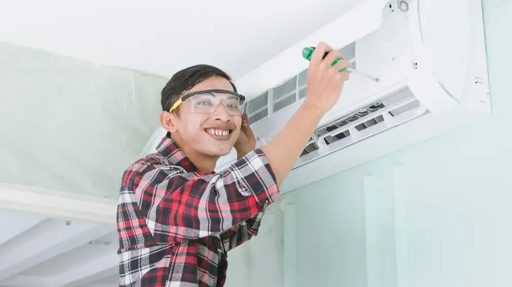 Technician servicing a wall-mounted air conditioning unit indoors